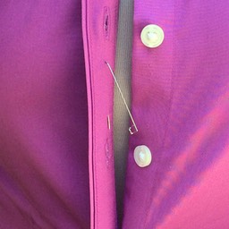 PINX is inserted into the right side placket, between the button holes. 