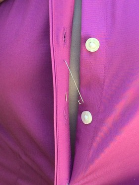 PINX is inserted into the right side placket, between the button holes. 